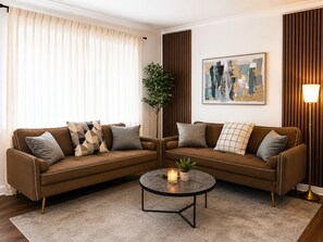 Ein Wohnzimmer mit einem braunen Sofagarnitur, einem runden Couchtisch und einem Blumentopf.