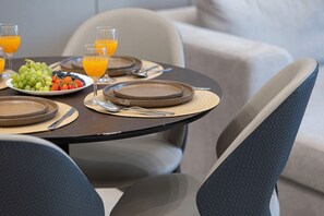 A dining table set with plates, cutlery, and a glass of orange juice. - 1BHK, Burj Khalifa View Business Bay (Dubai)