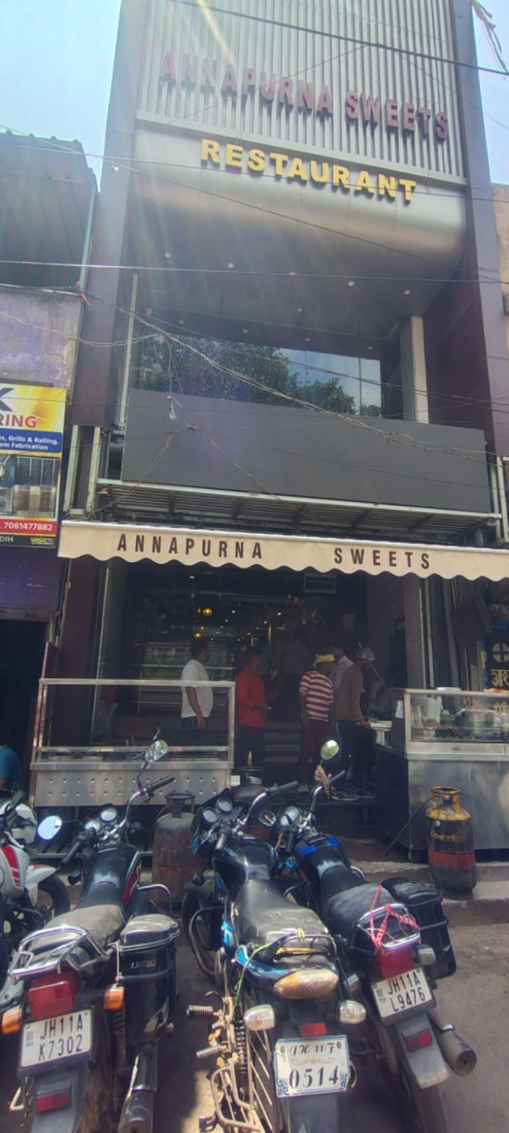 A two-story building with a sign for 'Annapurna Sweets Restaurant' on the upper level.