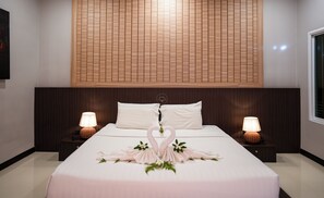 Ein Hotelzimmer mit einem großen Bett, zwei Nachttischlampen, einem Holzkopfschild und einer dekorativen Schwan-Dekoration.