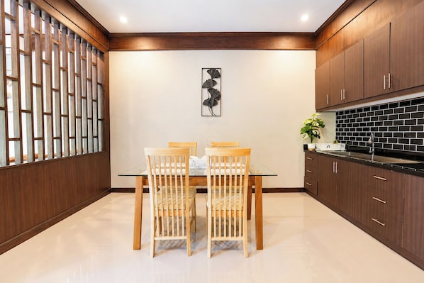 A modern kitchen with wooden cabinets, a glass dining table, and a decorative wall piece.