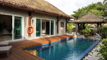 A poolside area with a wooden deck, a thatched-roof structure, and a lifebuoy.