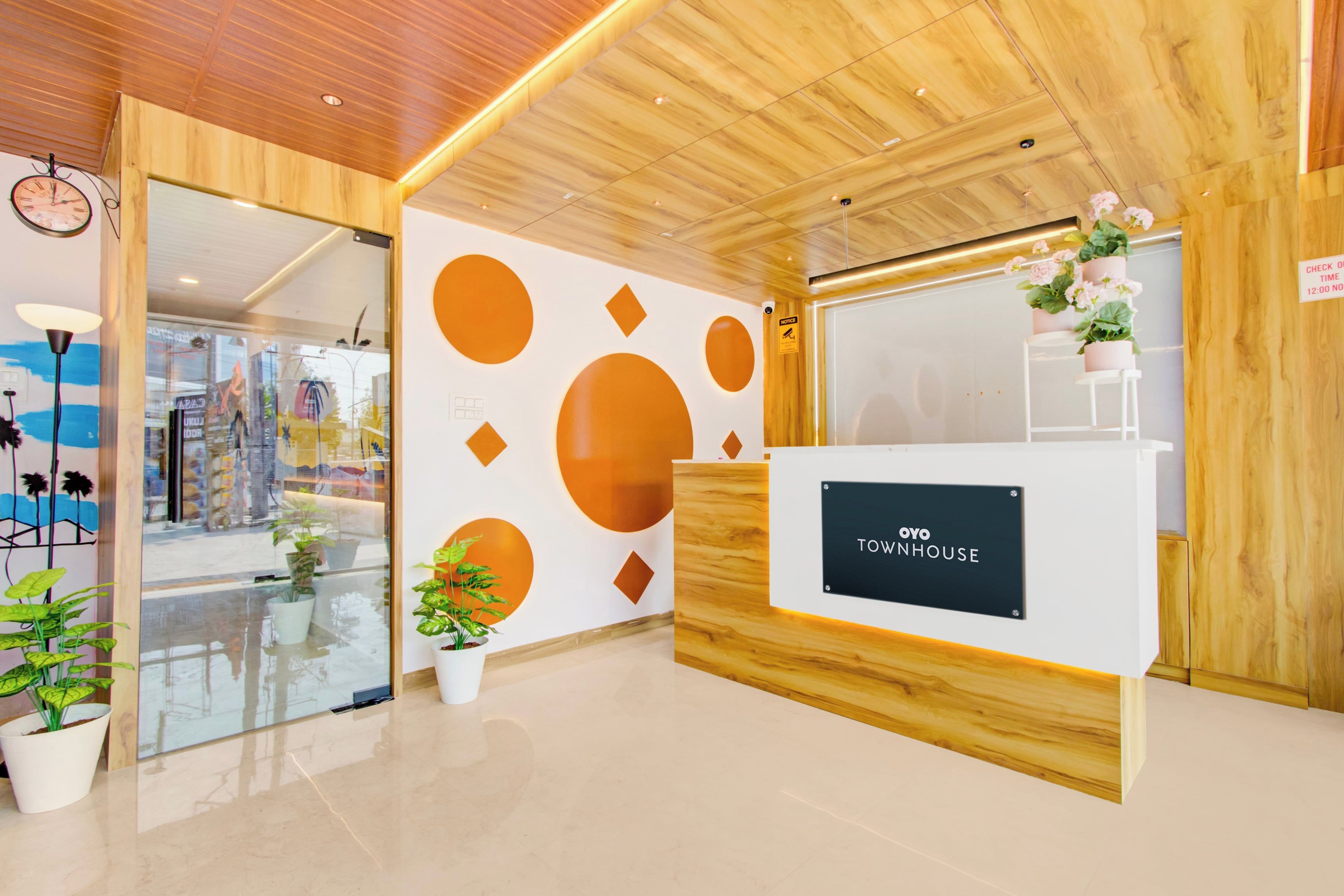 Un mostrador de recepción con un letrero que dice 'TOWNHOUSE' en un interior moderno con detalles de madera y decoraciones geométricas en la pared.