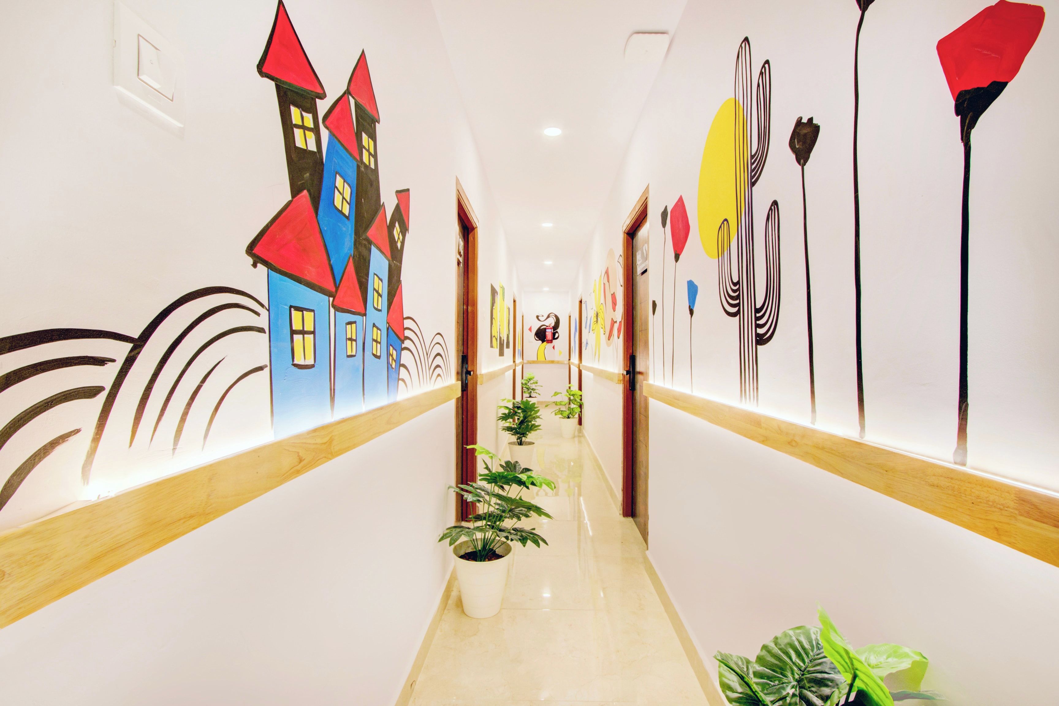 Un pasillo con un mural a la izquierda que muestra casas coloridas y arte abstracto a la derecha.