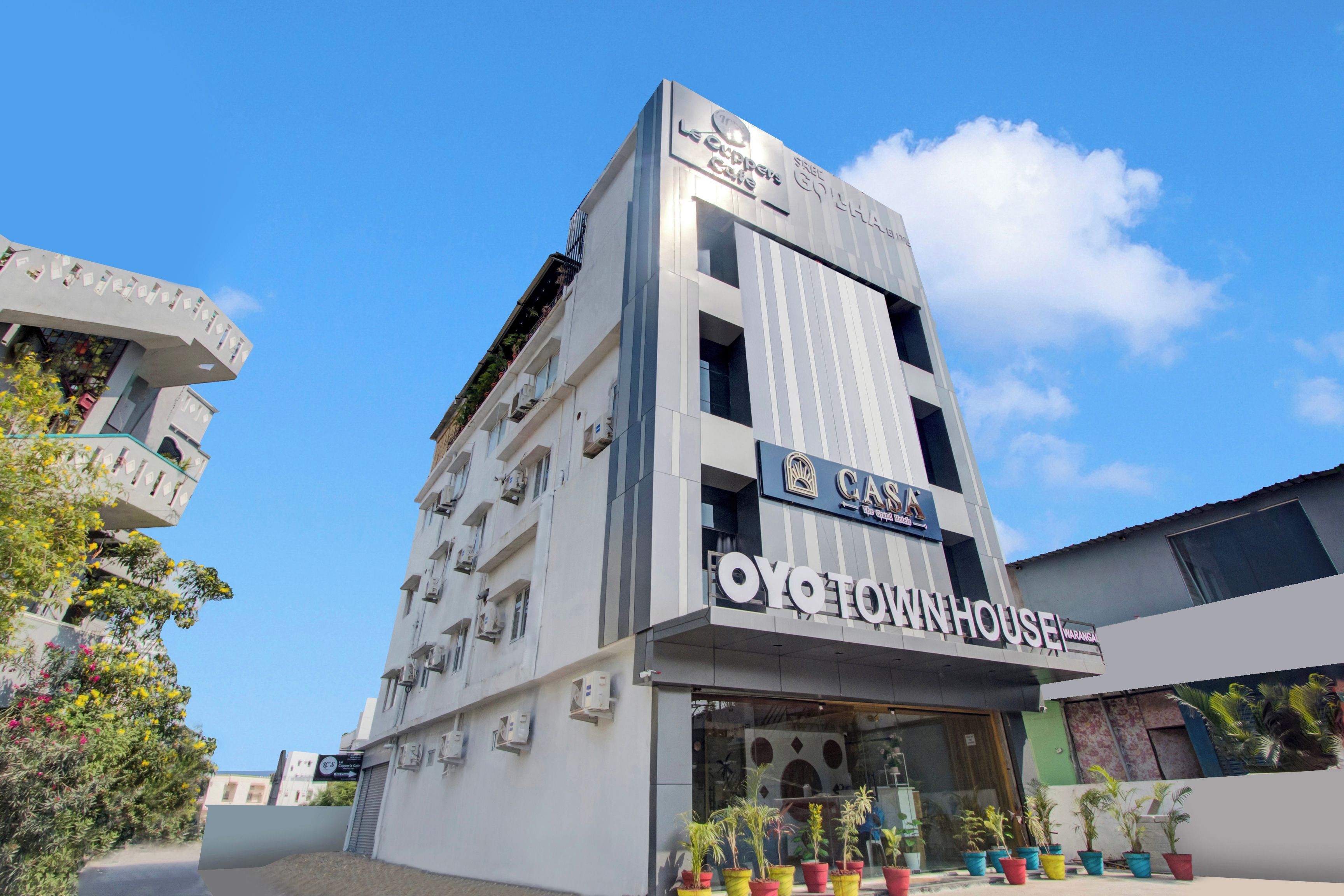 Un edificio de varios pisos con un letrero que dice 'CASA', la marca 'OYO TOWNHOUSE' y un letrero que indica 'Le Creperie's Cafe'.