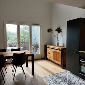 Eine moderne Küche mit einem Holzespeisetisch, Stühlen, einem schwarzen Kühlschrank und einem Schrank mit einer Blumenvase.