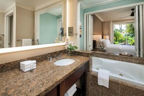 A hotel bathroom with a granite countertop sink, a large mirror, a bathtub, and a view of a bedroom with a bed and a nightstand. - Westin Princeville Ocean Resort Villas — 2BR Villa, Thanksgiving Week (Princeville)