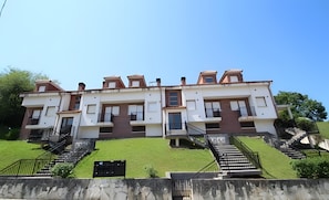Edifício residencial com vários andares, escadaria central, varandas e telhado plano.