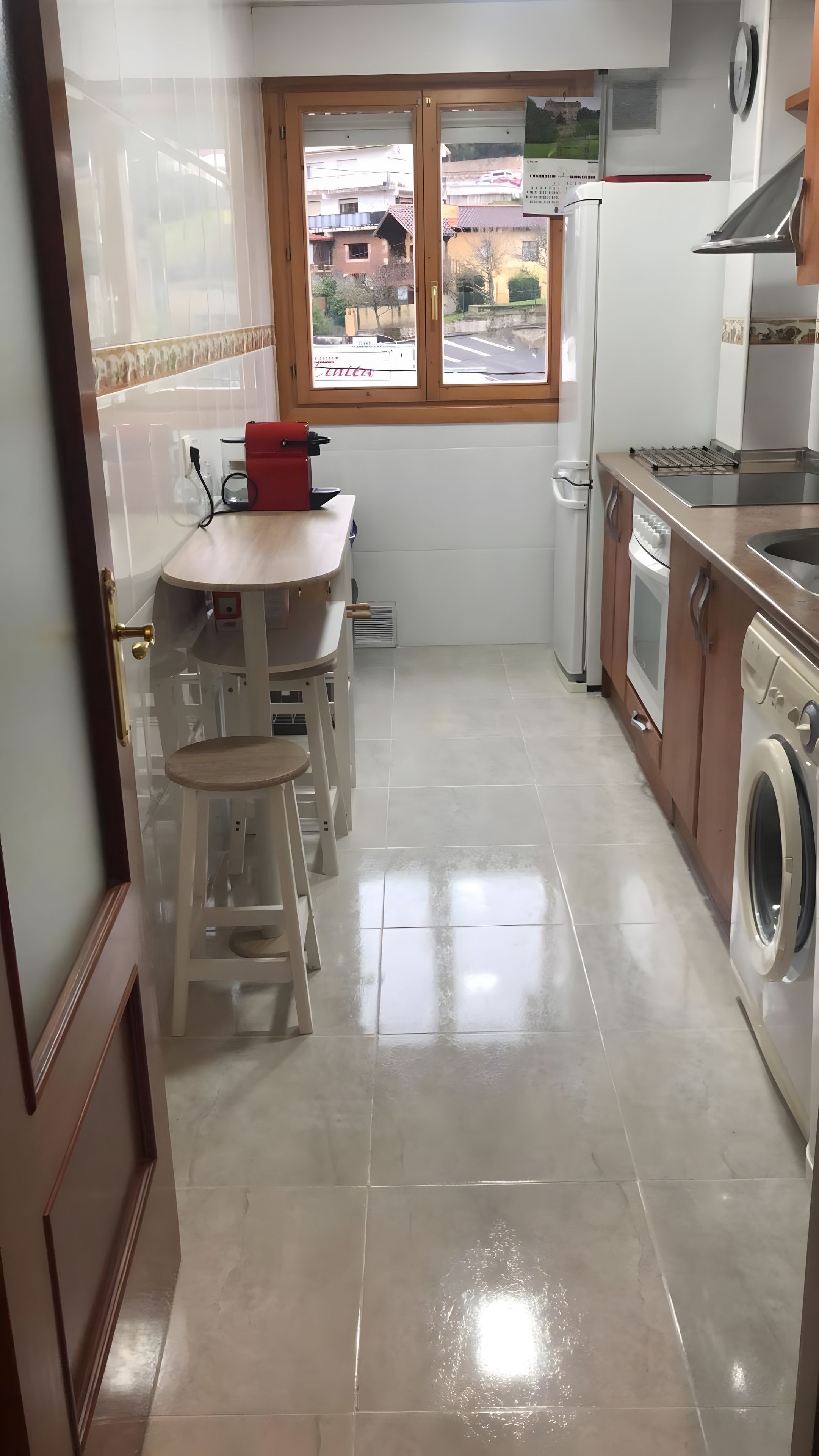 Una cocina compacta con ventana, lavadora y un pequeño comedor.