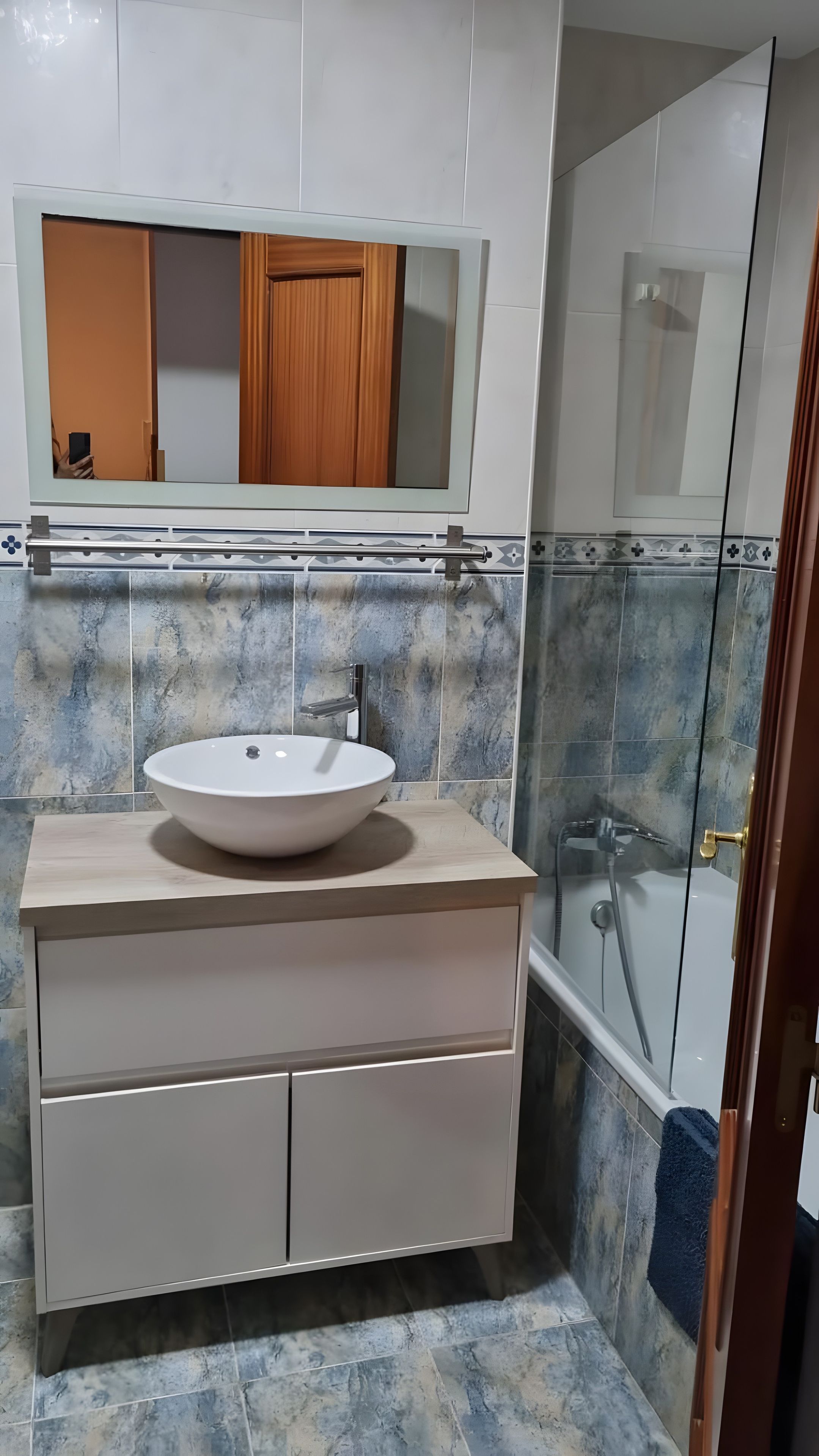 Une salle de bain avec un lavabo blanc, un miroir au-dessus et un espace douche.