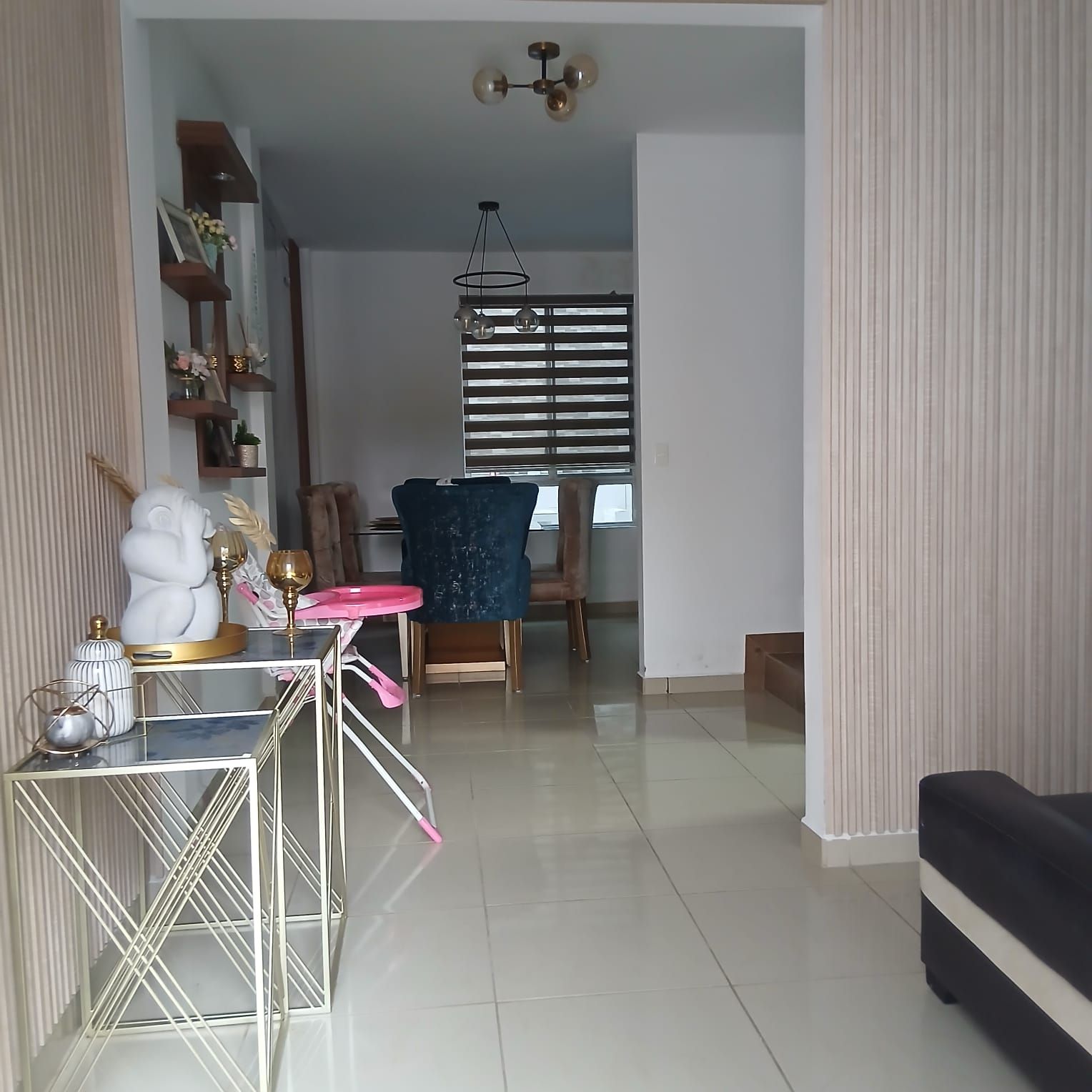 A modern living room with a dining area, featuring a sofa, a dining table with chairs, and a decorative lamp.
