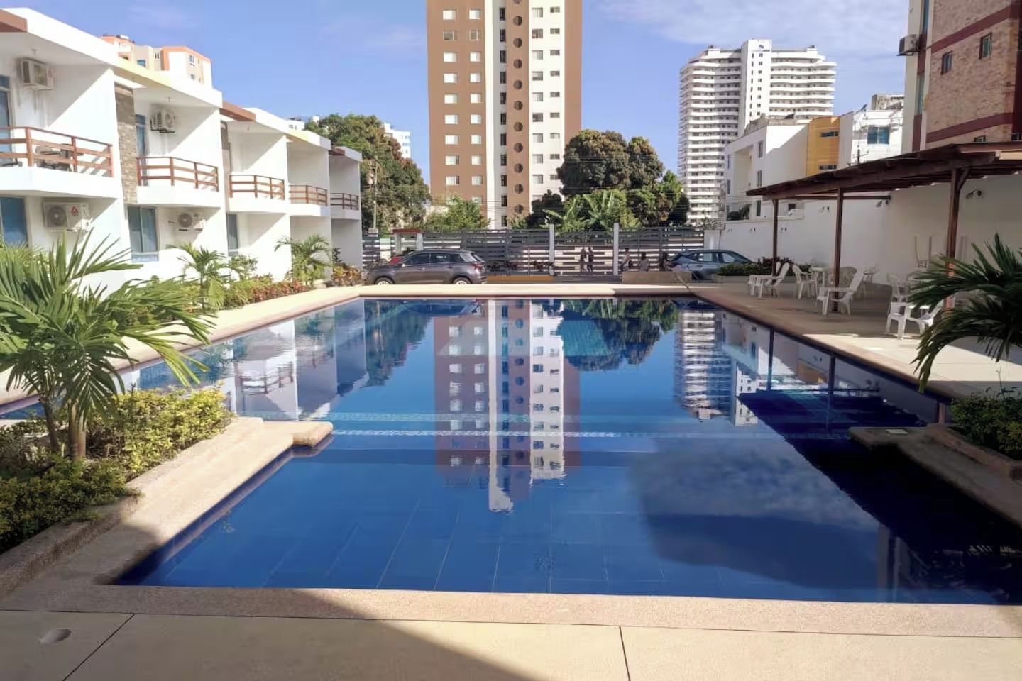 A swimming pool with a clear view of surrounding buildings, including a tall residential tower.