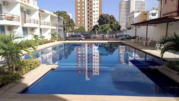 A swimming pool with a clear view of surrounding buildings, including a tall residential tower.