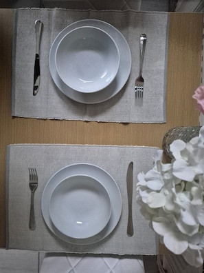 Een gedekte tafel met twee borden, een mes en een vork, en een placemat.