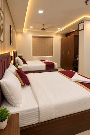 A hotel room with two beds, a ceiling fan, a clock, and a window with a view. - SRK Clasic (Chennai)