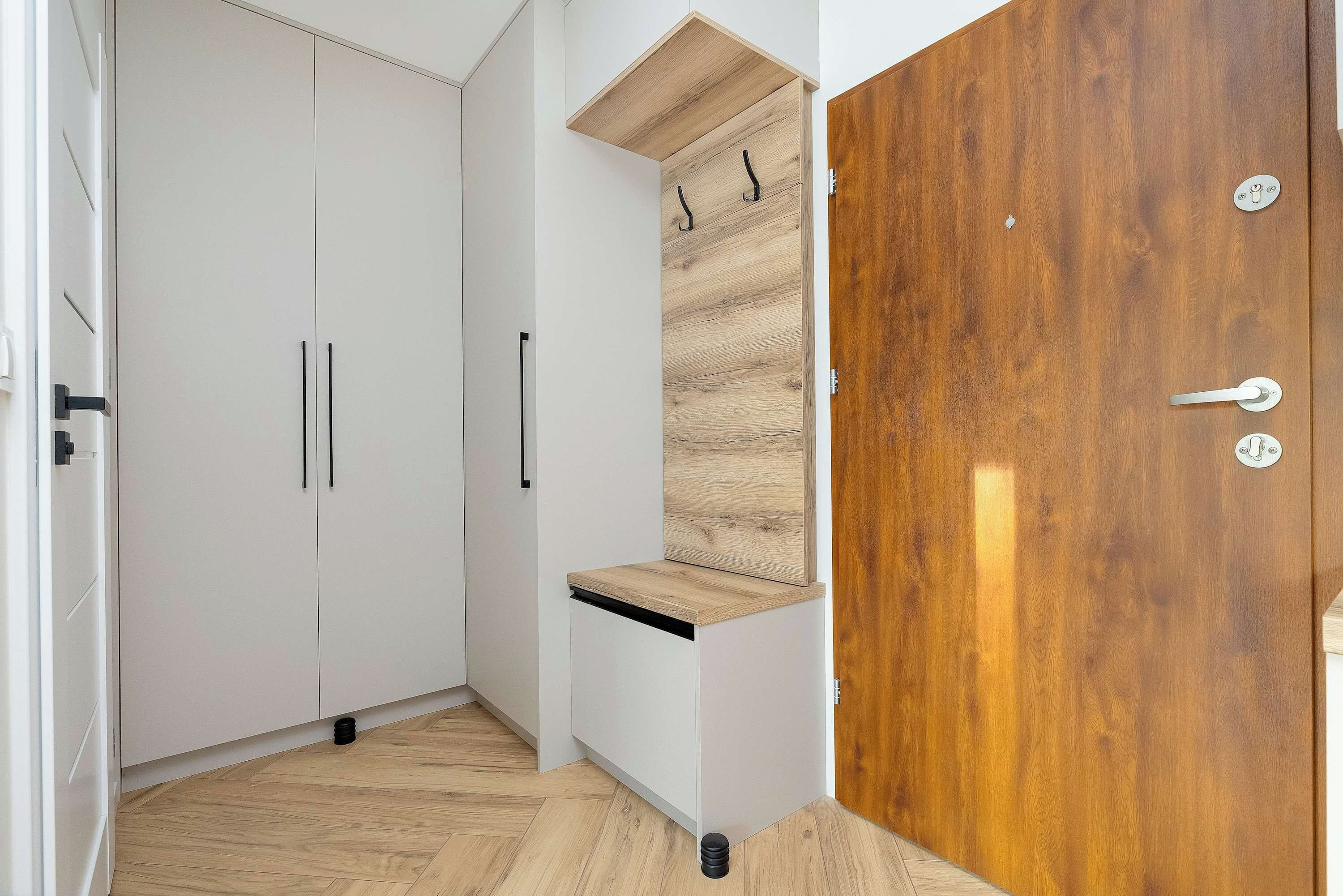 Una habitación con un armario blanco, una puerta de madera y un estante pequeño.