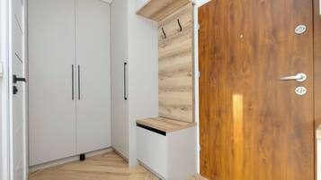 A room with a white wardrobe, a wooden door, and a small shelf.