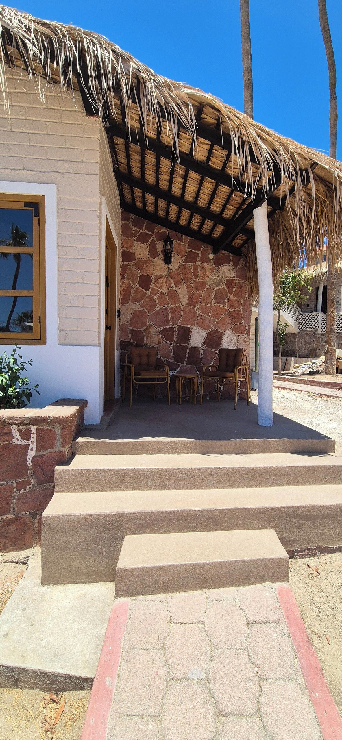 A building with a thatched roof, stone walls, and a seating area with chairs.