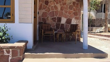 A building with a thatched roof, stone walls, and a seating area with chairs.
