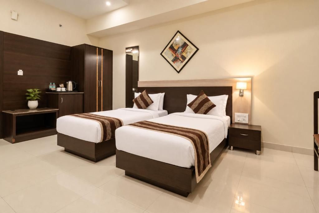A hotel room with two beds, a nightstand, a bedside table, a wall-mounted artwork, and a cabinet with a plant.