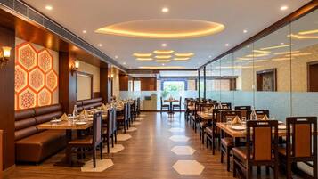 A restaurant with hexagonal patterned walls, wooden flooring, and a central aisle leading to a view of greenery.