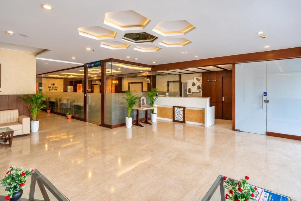 A hotel lobby with a reception desk, a seating area, and a glass partition.