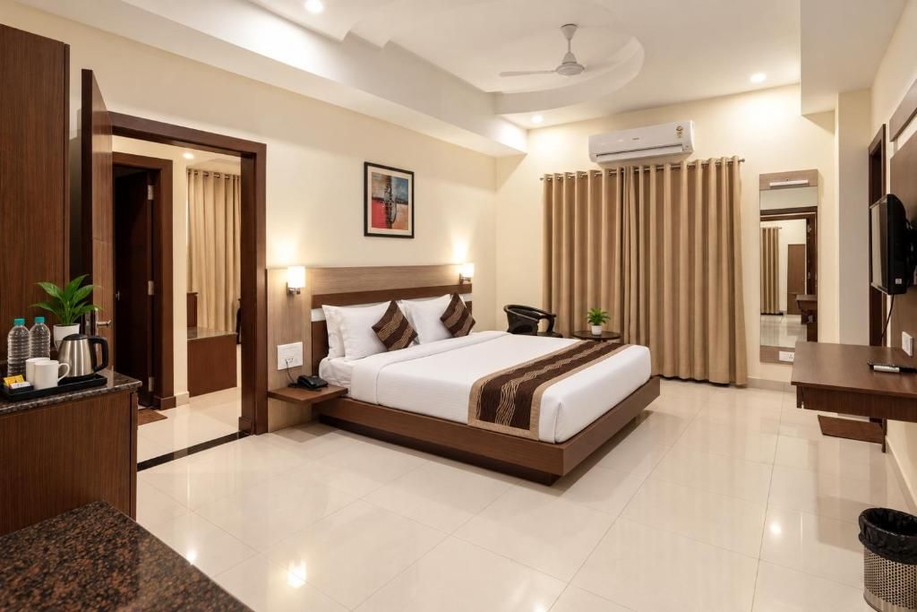 A hotel room with a bed, bedside table, lamp, air conditioning unit, and a television.