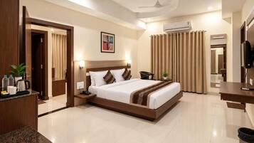 A hotel room with a bed, bedside table, lamp, air conditioning unit, and a television.