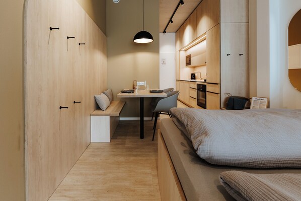 Ein kleines Schlafzimmer mit Bett, Schreibtisch und Sitzecke.