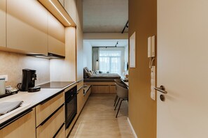 Eine moderne Küche mit Kaffeemaschine, ein Essbereich mit einer Couch und Blick ins Freie.