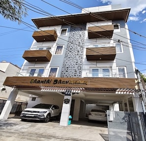 A multi-story building with a parking garage underneath. - Viswa Inn by Azalea (Madurai)