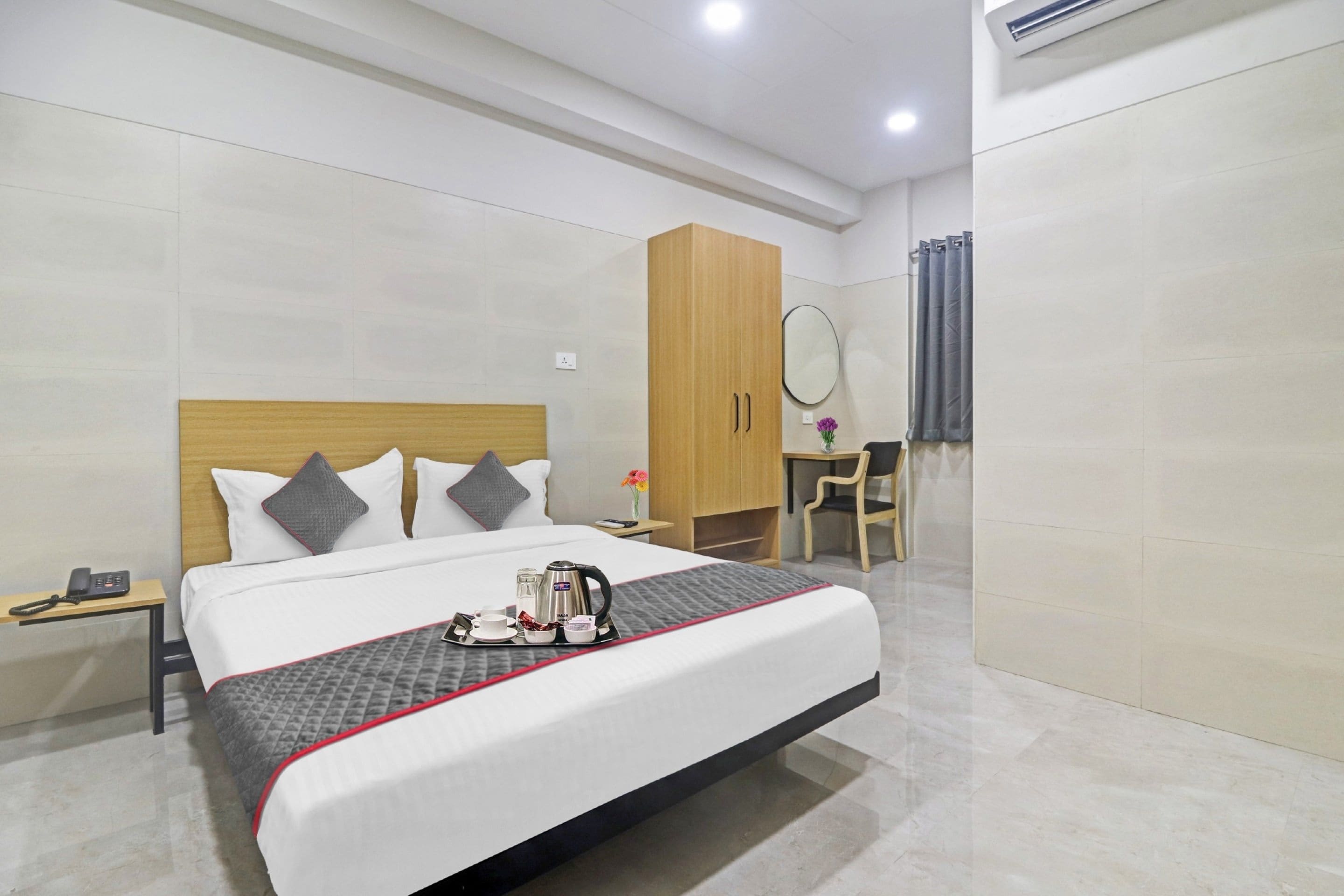 Habitación de hotel con una cama grande, una mesita de noche, un escritorio con silla, un armario y un espejo.