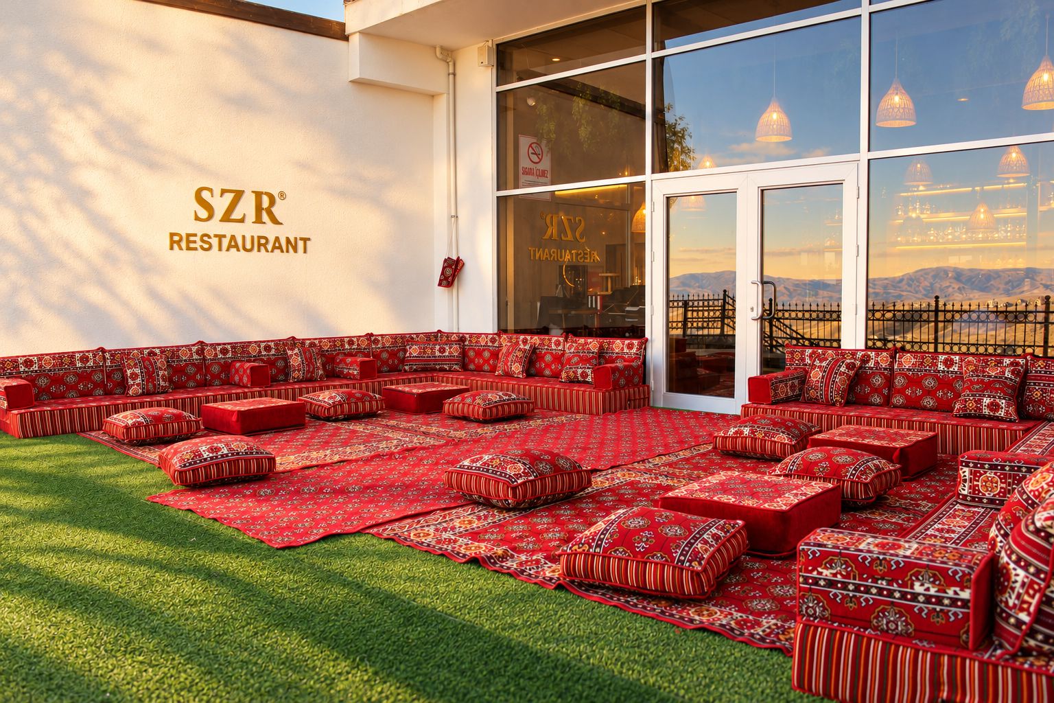 An outdoor seating area with patterned cushions and rugs, a restaurant sign, and a view of the mountains.