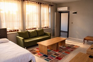 A room with a bed, a green sofa, a wooden table, and a colorful rug. - SZR HOTEL & RESTAURANT (ANKARA)