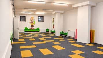 A spacious room with a patterned carpet, white walls, and a cartoon mural on the back wall.