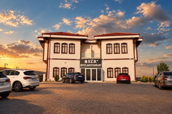 A two-story hotel with a sign reading 'SZR HOTEL & RESTAURANT' and a parking lot with several cars. - SZR HOTEL & RESTAURANT (ANKARA)