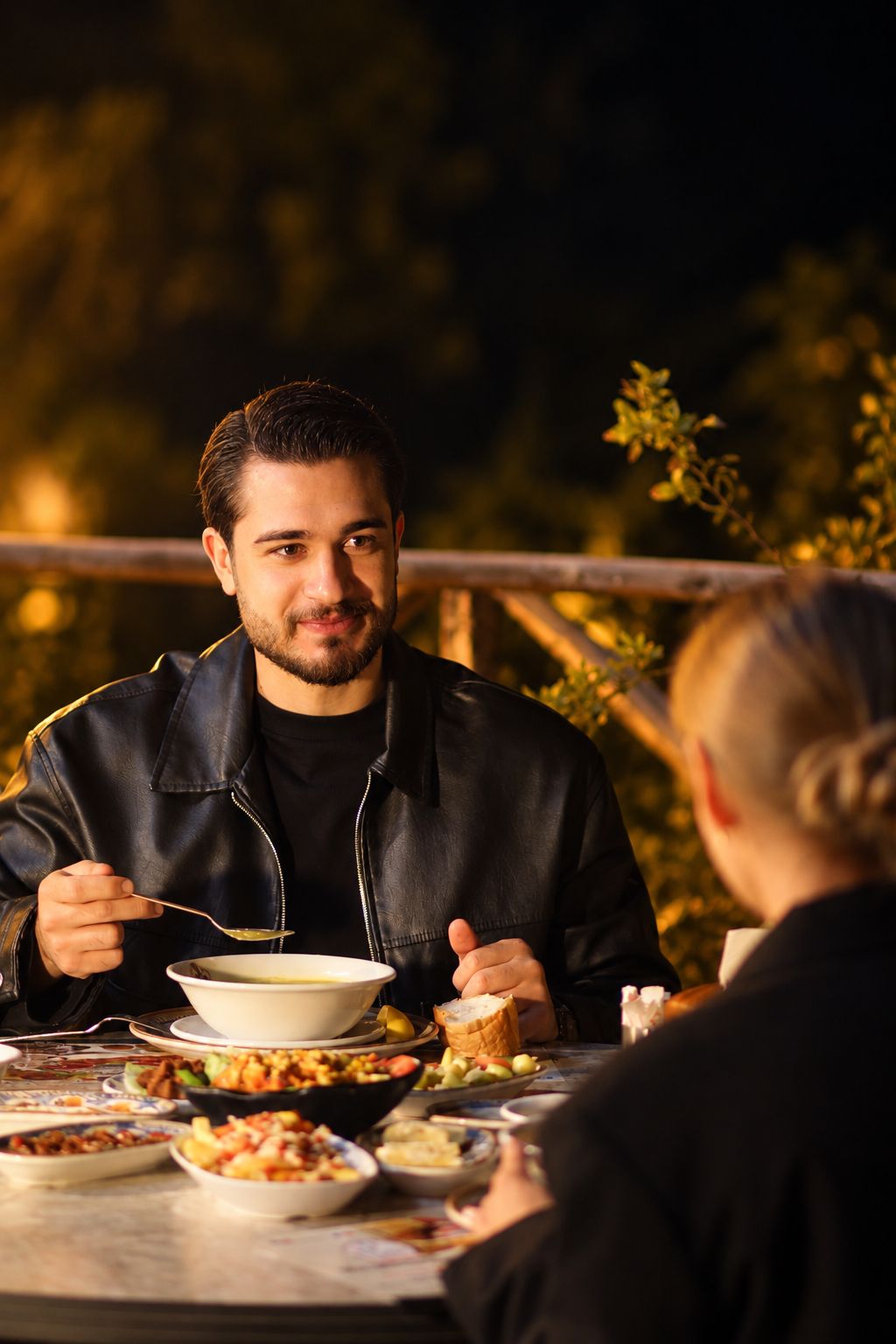 Una persona comiendo al aire libre en una mesa con varios platos.