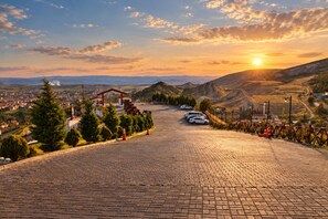 A paved road leading to a building with a sloped roof, surrounded by trees and parked cars. - SZR HOTEL & RESTAURANT (ANKARA)