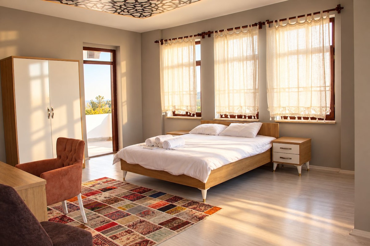 A bedroom with a bed, bedside tables, a chair, and a view of the outdoors.