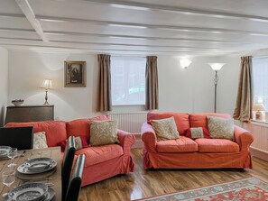 A living room with two sofas, a dining table set with plates and glasses, a framed picture on the wall, and a floor lamp. - 2 bedroom accommodation in Sherburn (Sherburn)