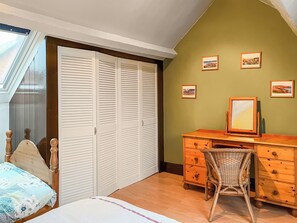 A bedroom with a bed, a wooden dresser, a wicker chair, a desk with a mirror, and a closet with louvered doors. - 2 bedroom accommodation in Sherburn (Sherburn)
