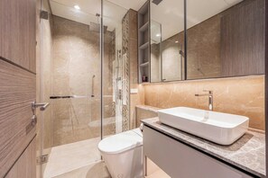 Un bagno moderno con doccia vetro, lavandino bianco e water.