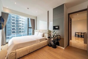 Una moderna camera d'hotel con un letto grande, un'area ristorazione e vista su un grattacielo.