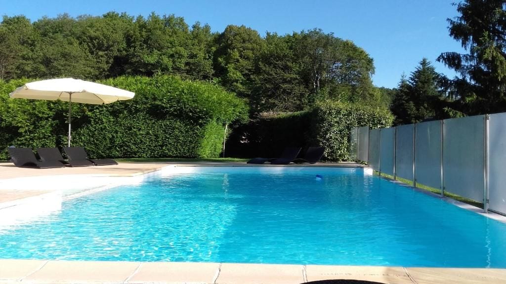 A swimming pool with lounge chairs and an umbrella.