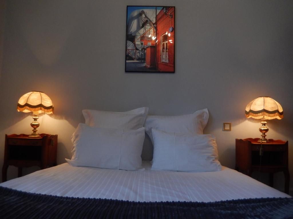 Un dormitorio con una cama, dos lámparas de noche, un cuadro en la pared y una mesita de noche.