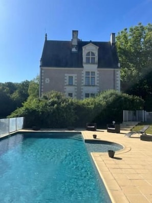 Una piscina con una casa al fondo.