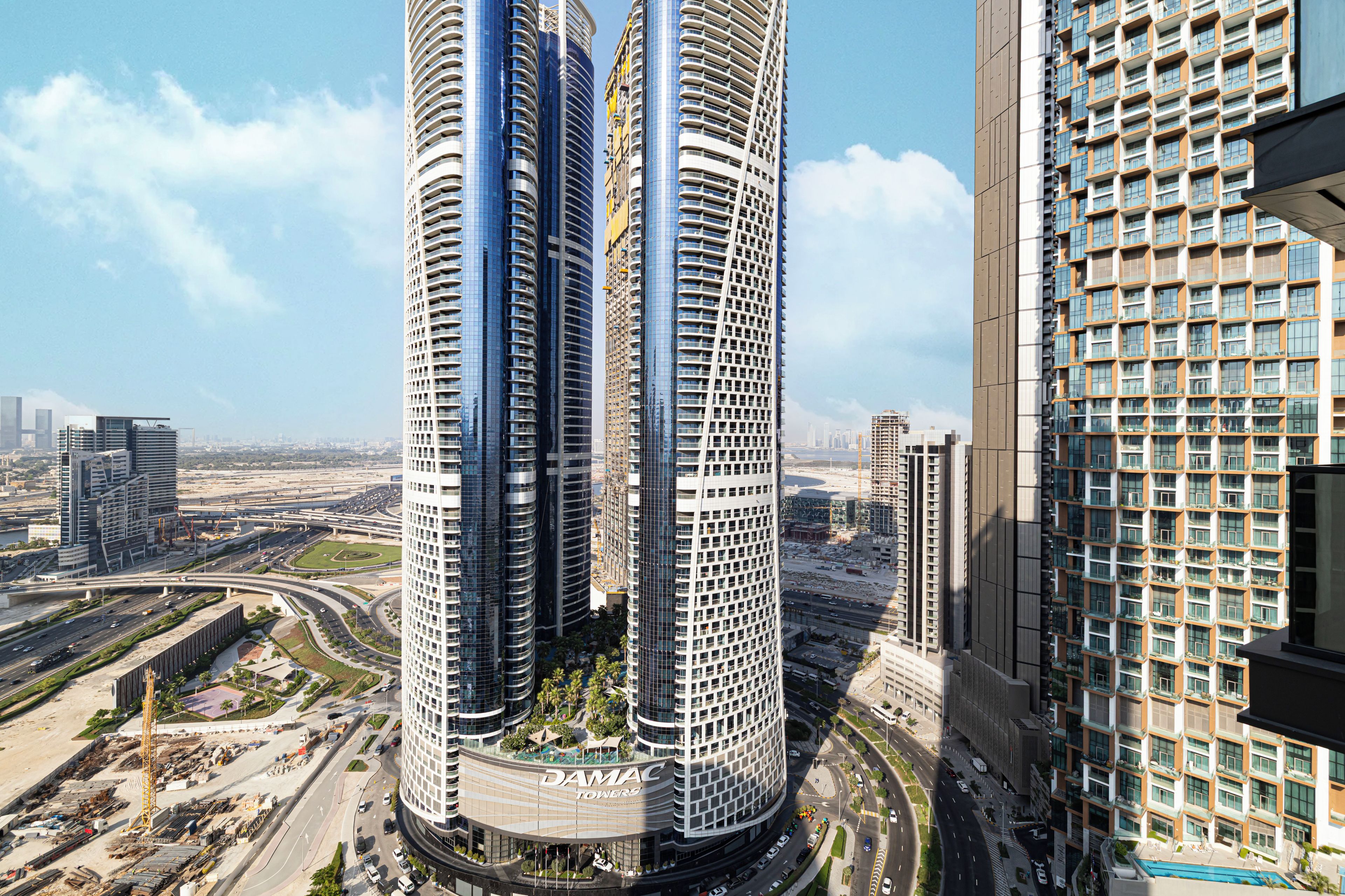 A high-rise building with a curved facade, multiple balconies, and a central courtyard with greenery.