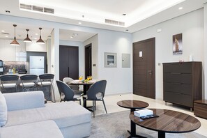A modern living room with a sofa, dining table, chairs, and a coffee table. - Business Bay Stylish 1BR , City View (Dubai)