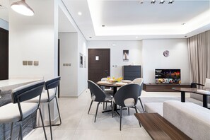 A modern living room with a dining area, a flat-screen TV, and a sofa. - Business Bay Stylish 1BR , City View (Dubai)