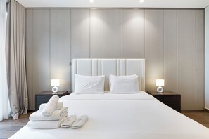 A hotel room with a large bed, two bedside lamps, and a stack of towels on the floor. - Business Bay Stylish 1BR , City View (Dubai)